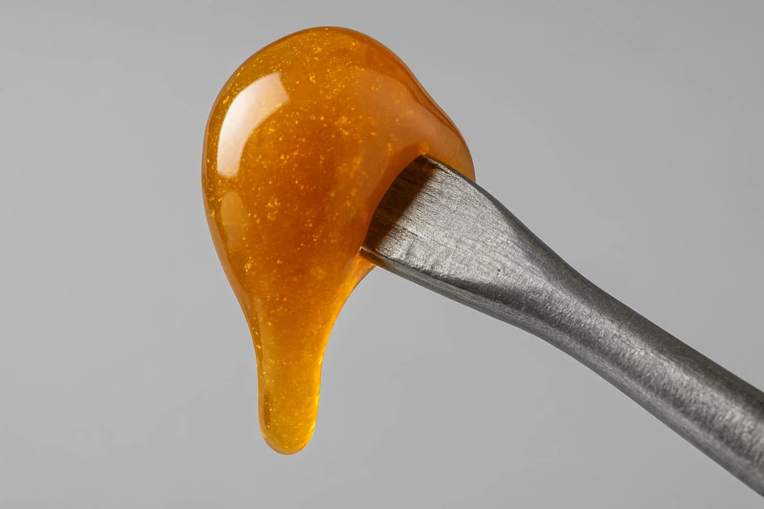 Gota de rosin CBD adherida a la punta de un dabber metálico