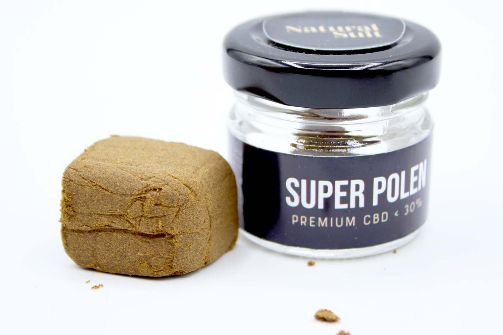 Tarro negro con polen CBD premium junto a bloque de resina