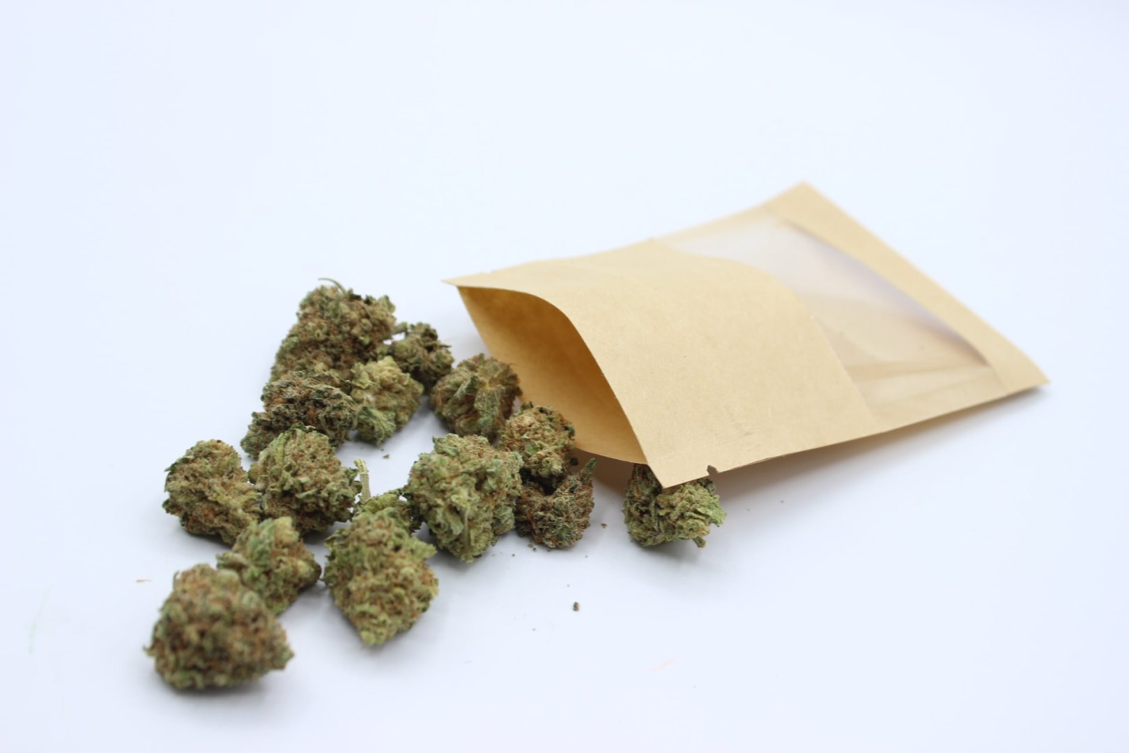 Bolsa kraft con ventana y cogollos de CBD frescos sobre fondo blanco