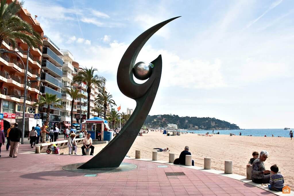 Monumento en el paseo marítimo de Lloret de Mar con tiendas y CBD shop en la zona