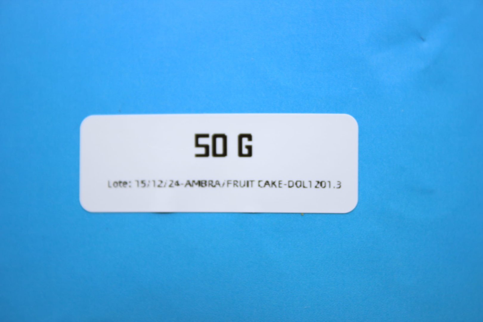 Detalle de número de lote en etiqueta blanca sobre packaging azul de flor CBD