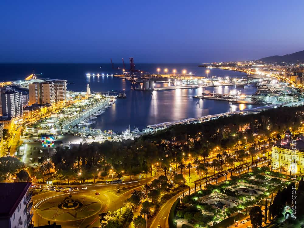 Vista nocturna del puerto de Málaga con luces y comercios, ideal para visitar una CBD shop
